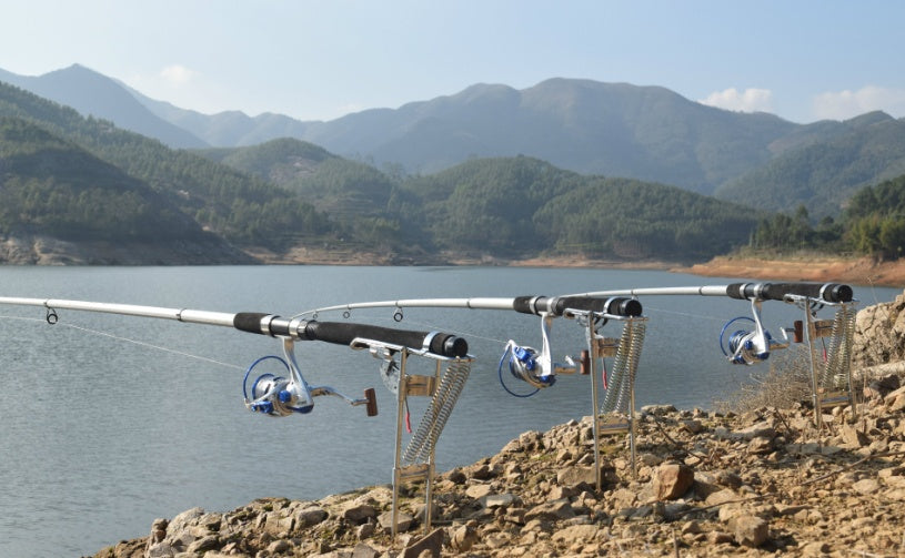  Four fishing rods with automatic hook setters on lakeside - professional multi-rod fishing setup ideal for Qatar waters and Gulf fishing, scenic outdoor fishing system

